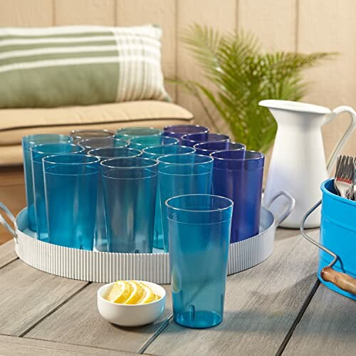 Set of blue glasses on a tray with a pitcher and a bowl of lemon slices.