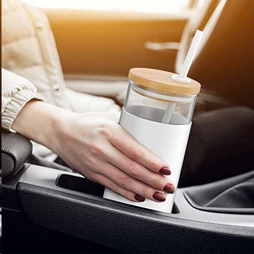 Person holding a travel mug with straw in a car cup holder